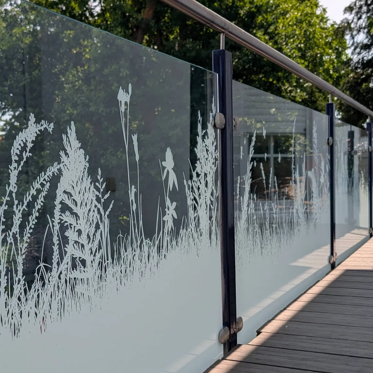 Pfostengeländer aus Aluminium mit Glasfüllung und Gräsermotiv an einer Terrasse